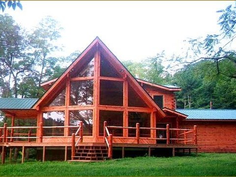 Custom log home with a large glass gable and wraparound deck