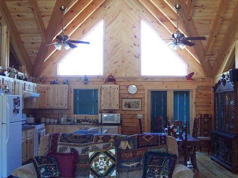 Open kitchen and living area with vaulted pine ceiling and exposed trusses