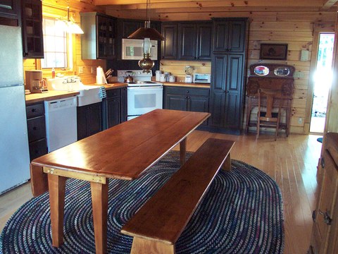 Custom kitchen with dark cabinetry, farmhouse sink, and a built-in dining table